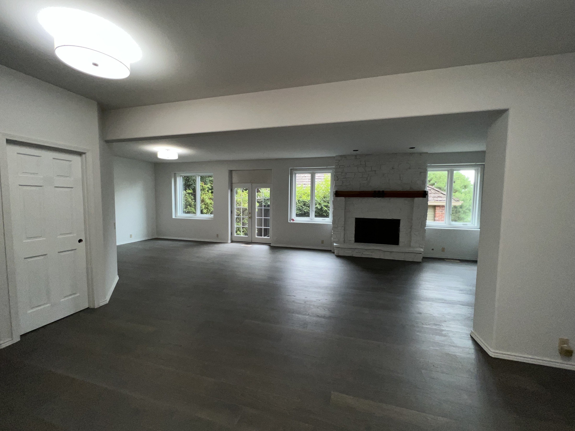 Lower-level room with a fireplace, white walls and dark flooring