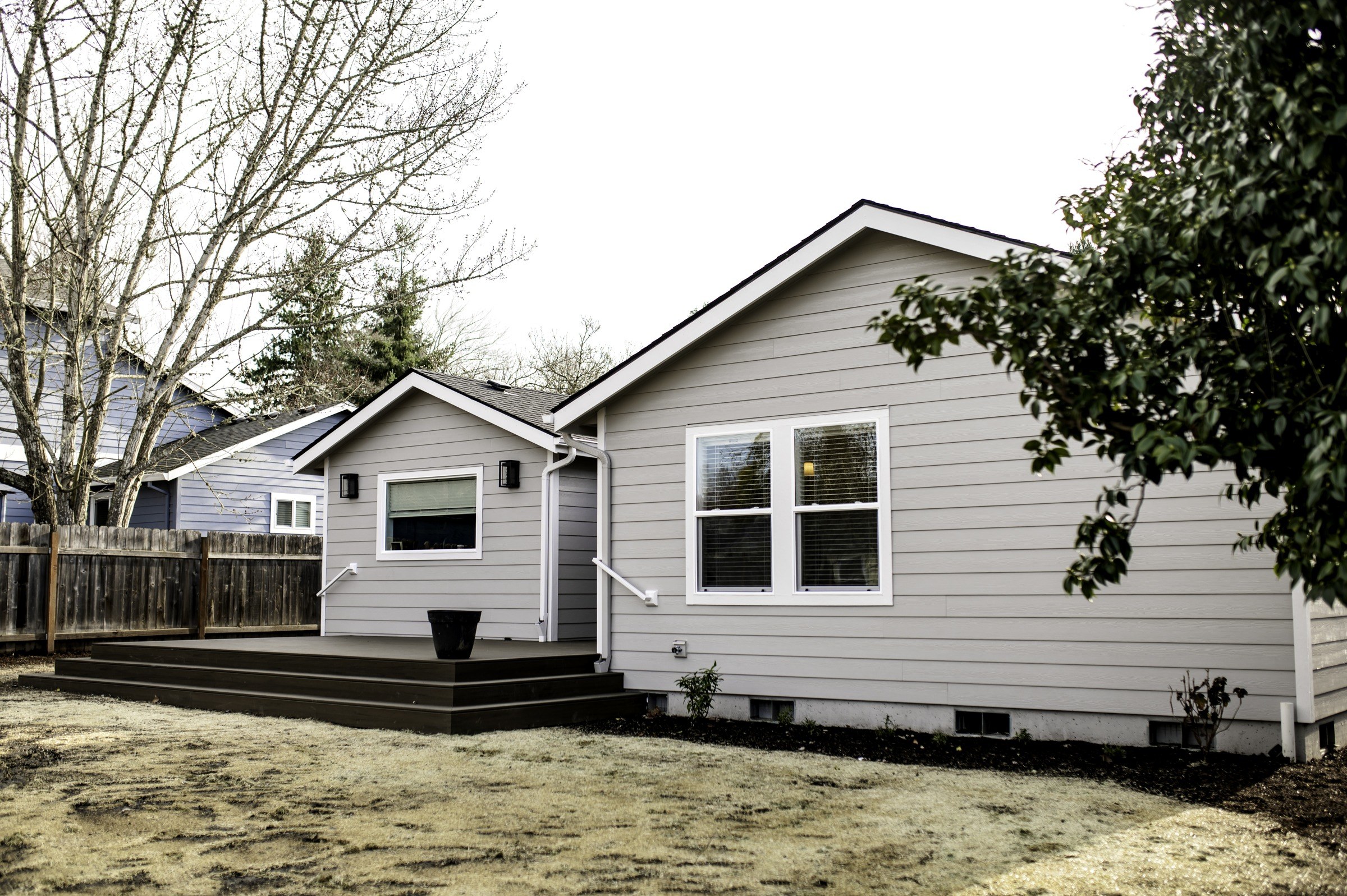 Gray rear elevation with two gables, a deck and lawn
