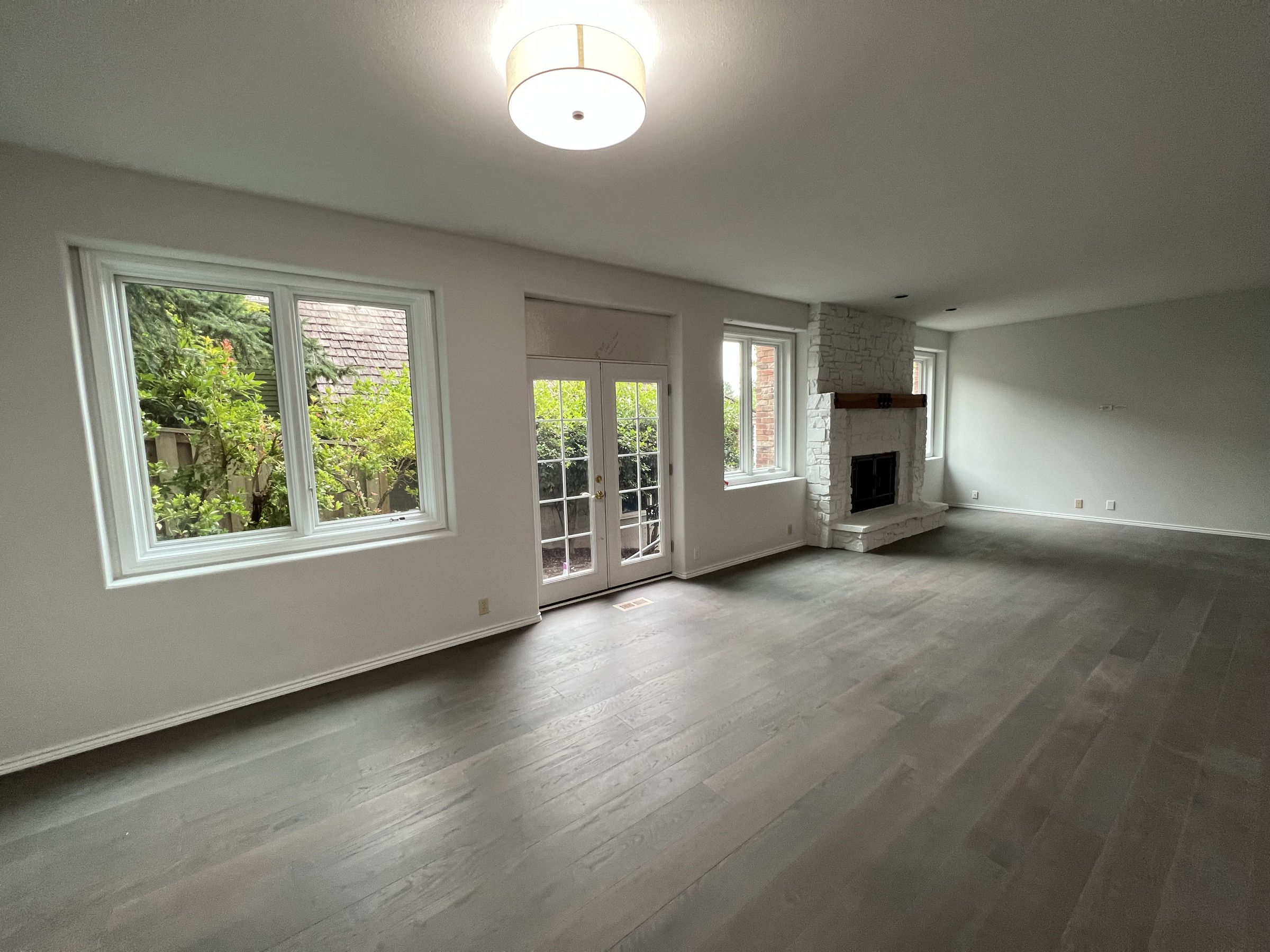 Basement living room with a fireplace, windows, and dark flooring