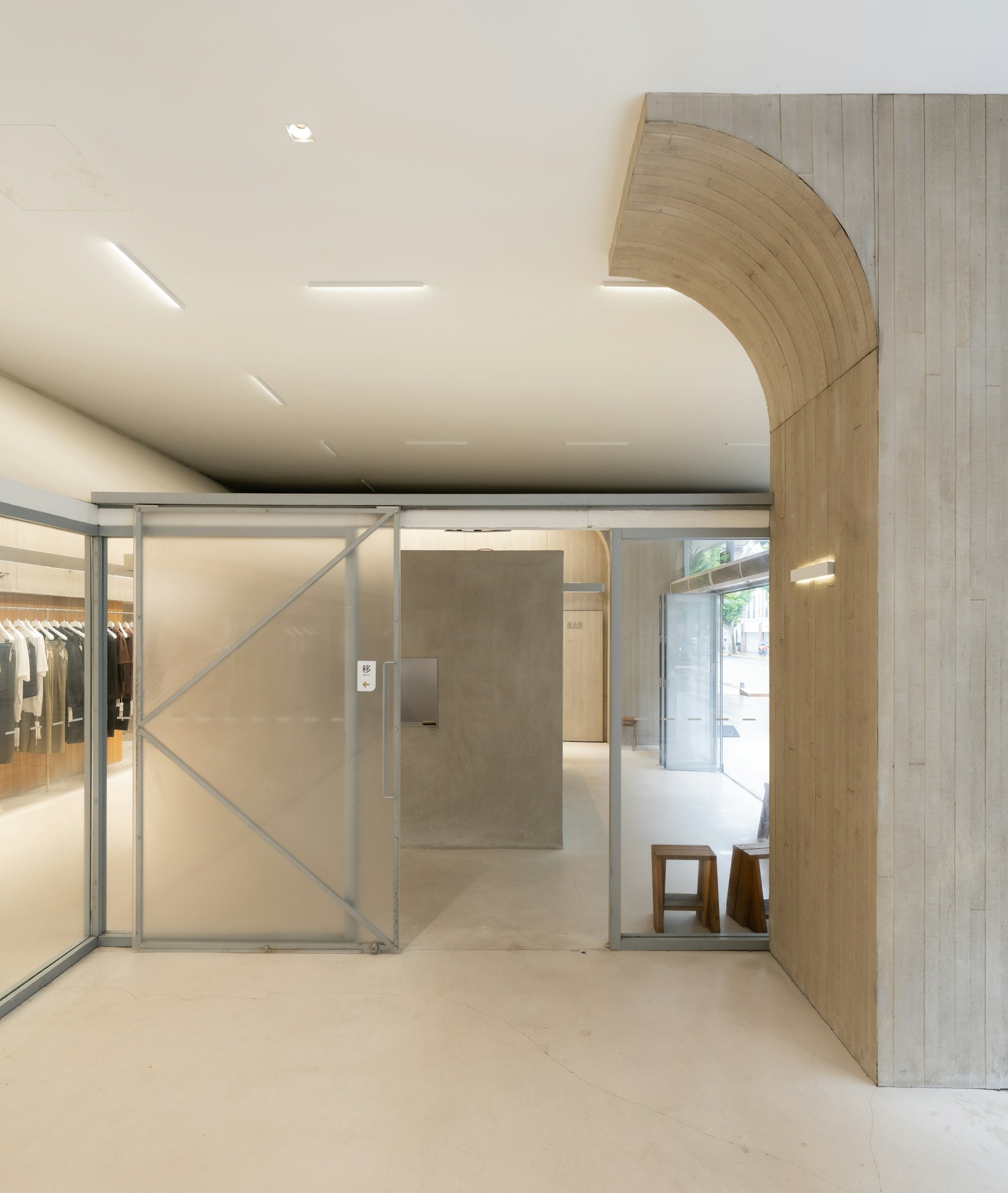 Retail interior with a curved concrete feature and glazed sliding partition.