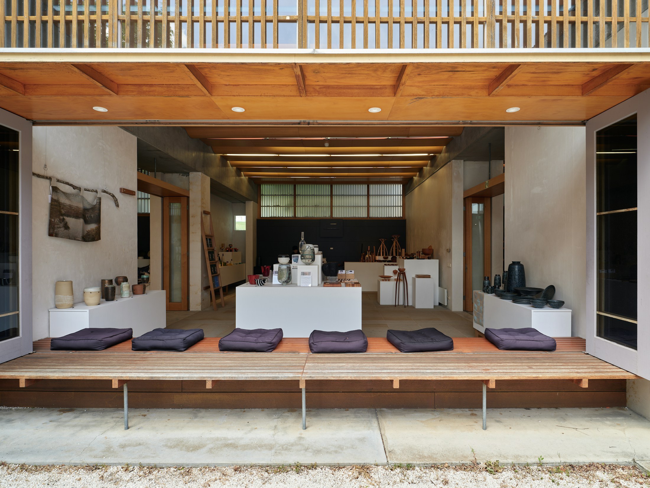 Timber display cabinetry and built-in seating beneath exposed framing.