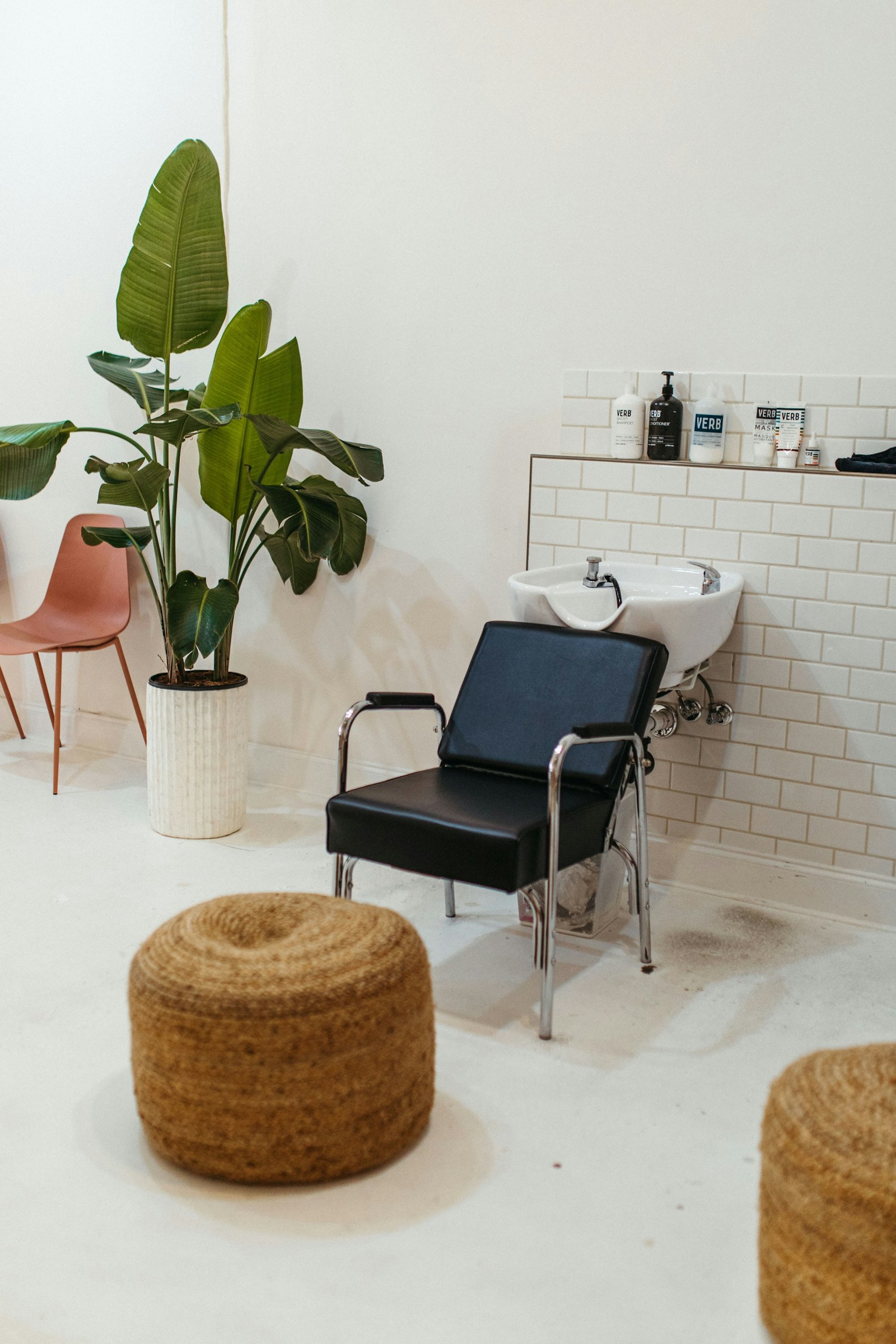Salon shampoo station with white tile and a planted waiting corner.