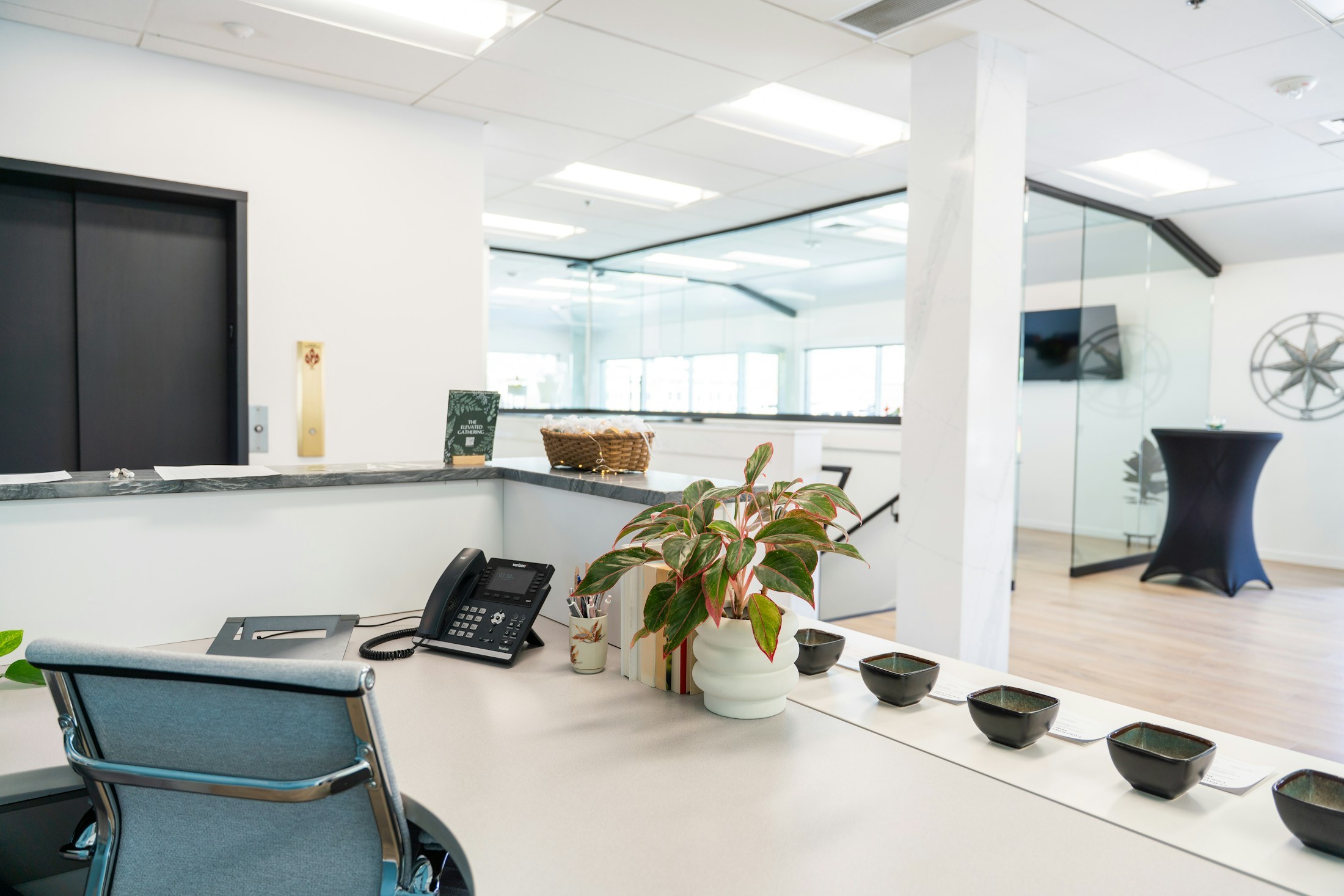 Bright reception counter beside glass-enclosed meeting rooms.