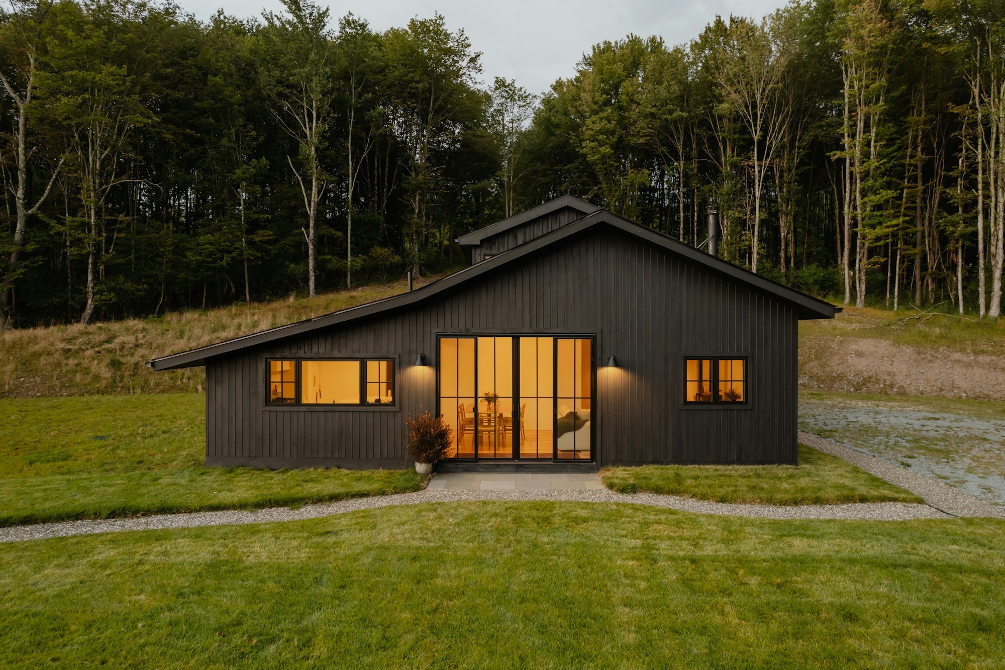 Dark wood-clad home with a gabled facade and illuminated glazed doors