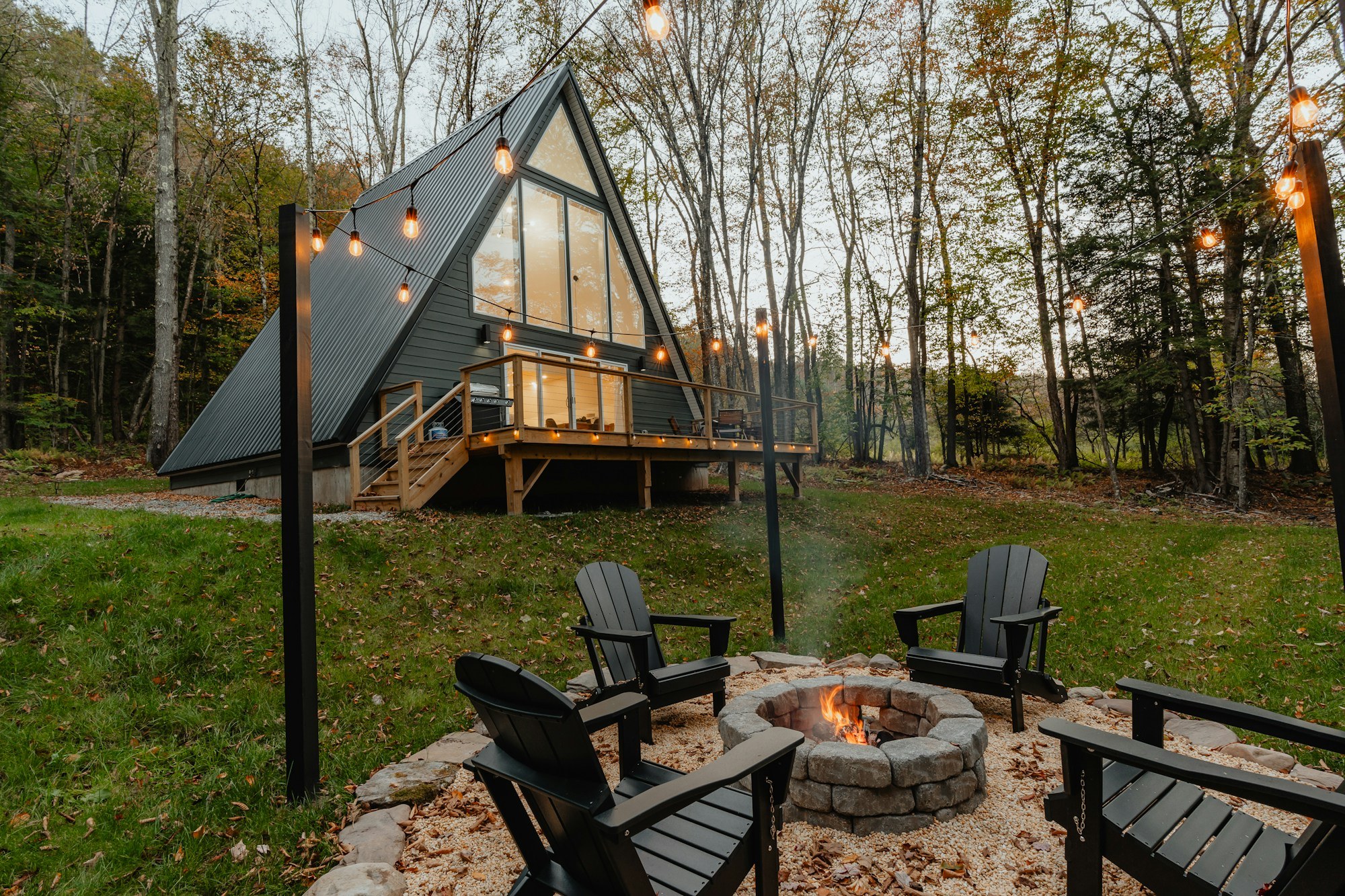 A-frame cabin with a glazed front, elevated deck and landscaped fire pit