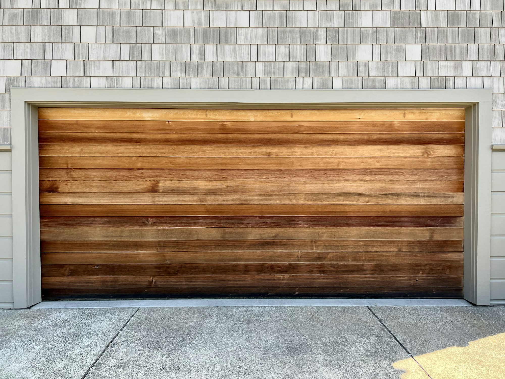 Wood garage door framed by pale shingle siding