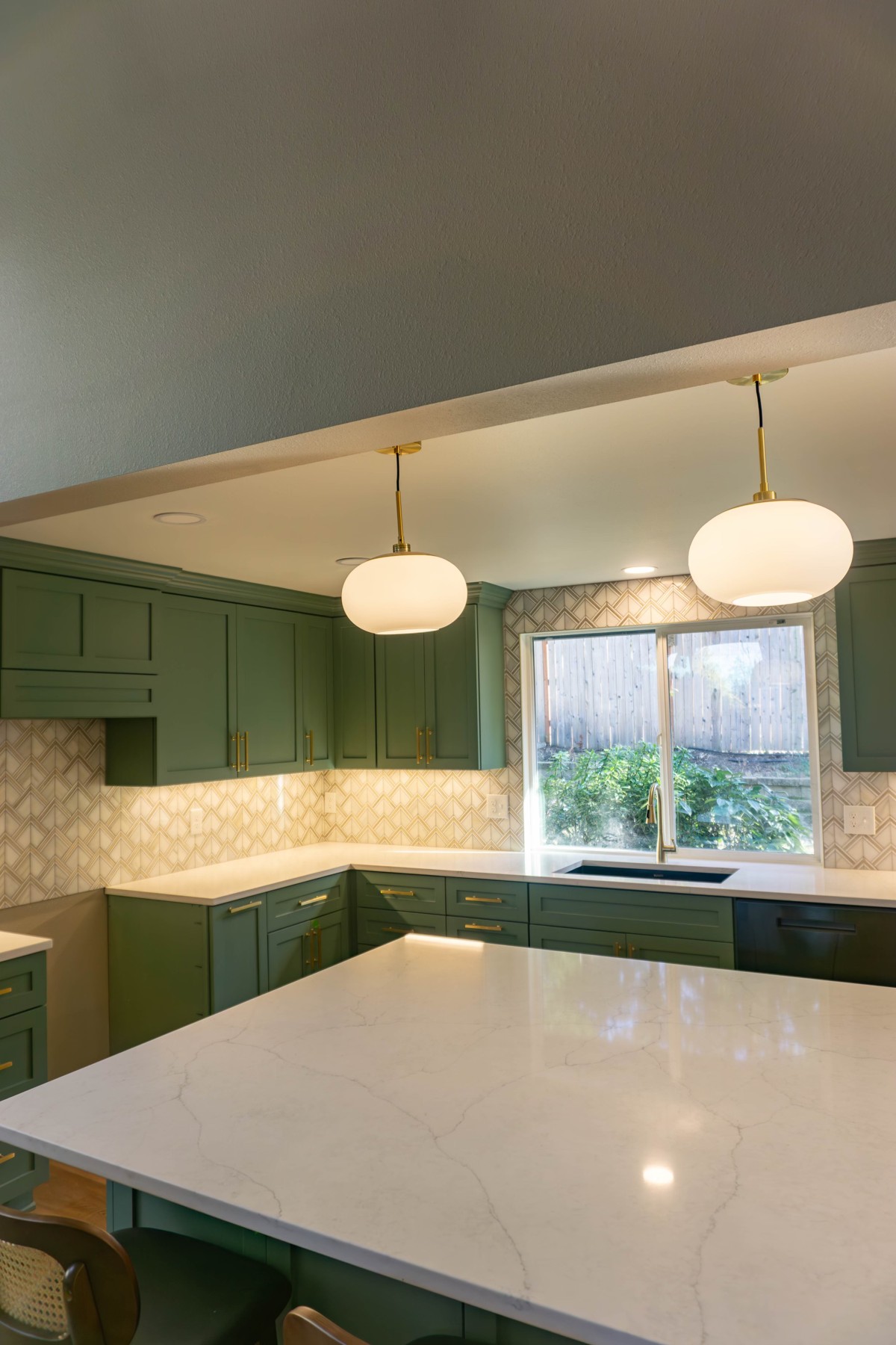 Resolution kitchen with green cabinetry, a pale island countertop, and pendant lights