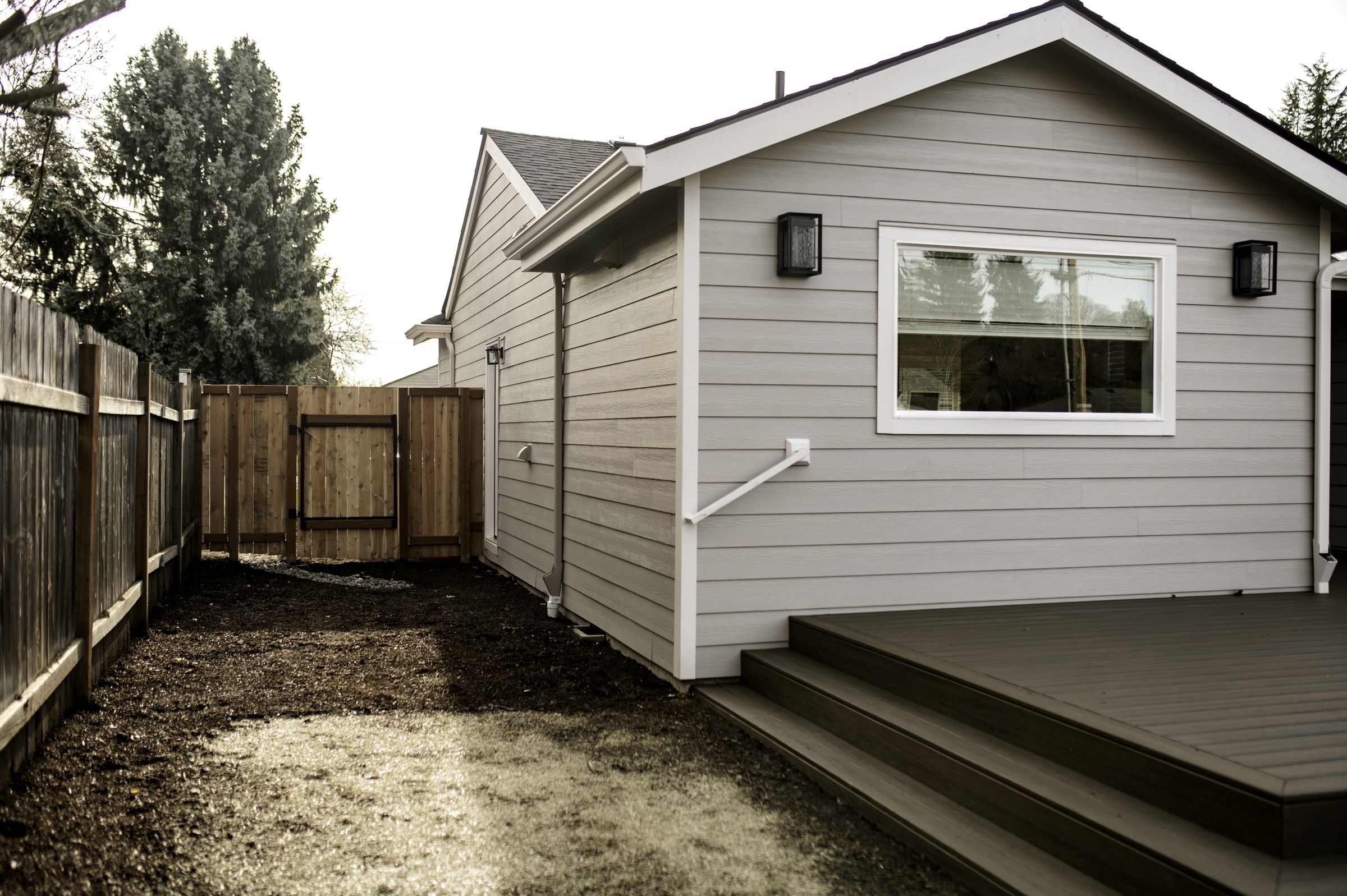 Light siding and white trim beside a deck with wide steps.