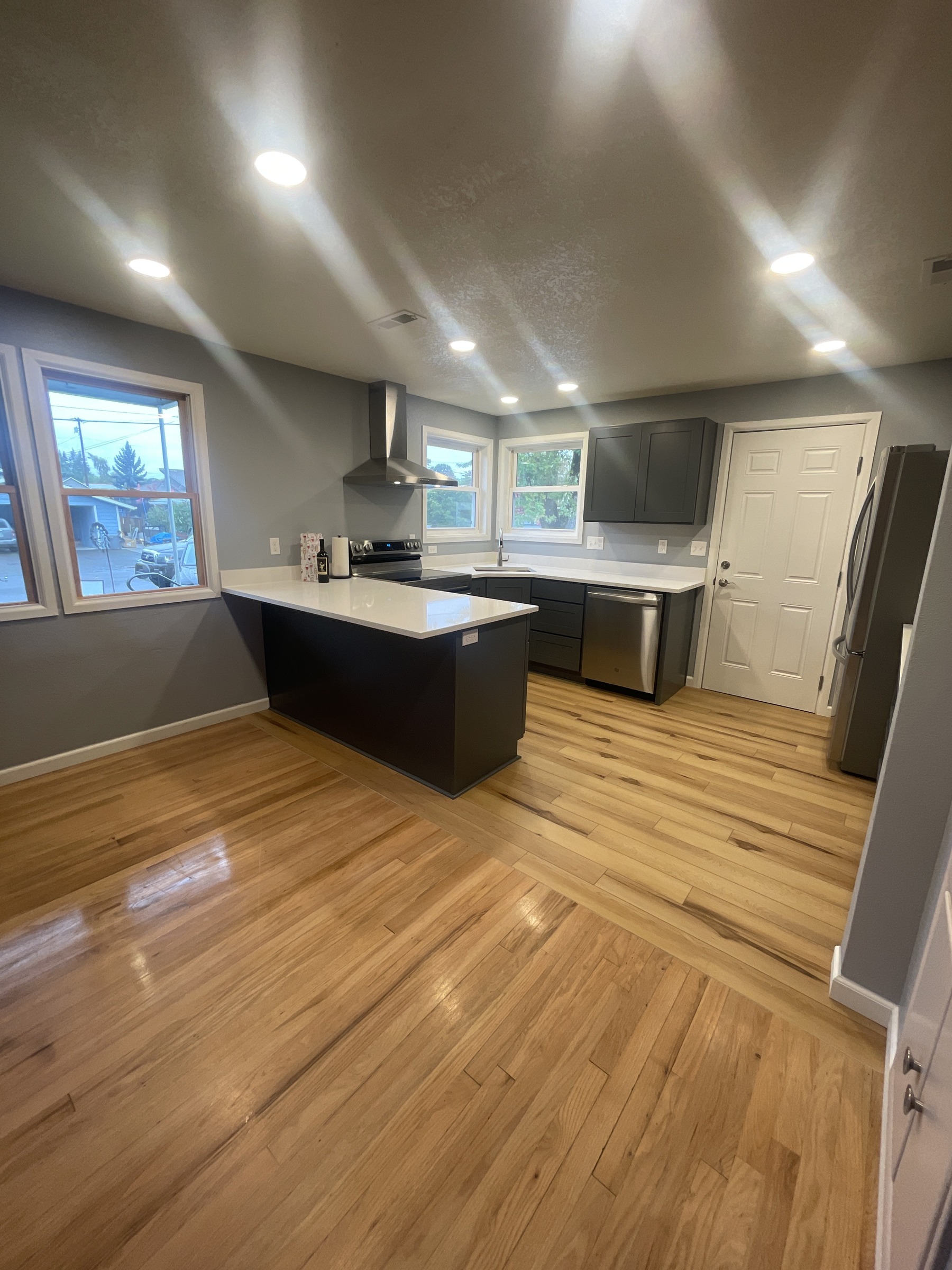 Gray kitchen with a dark island, pale countertop, and wood flooring