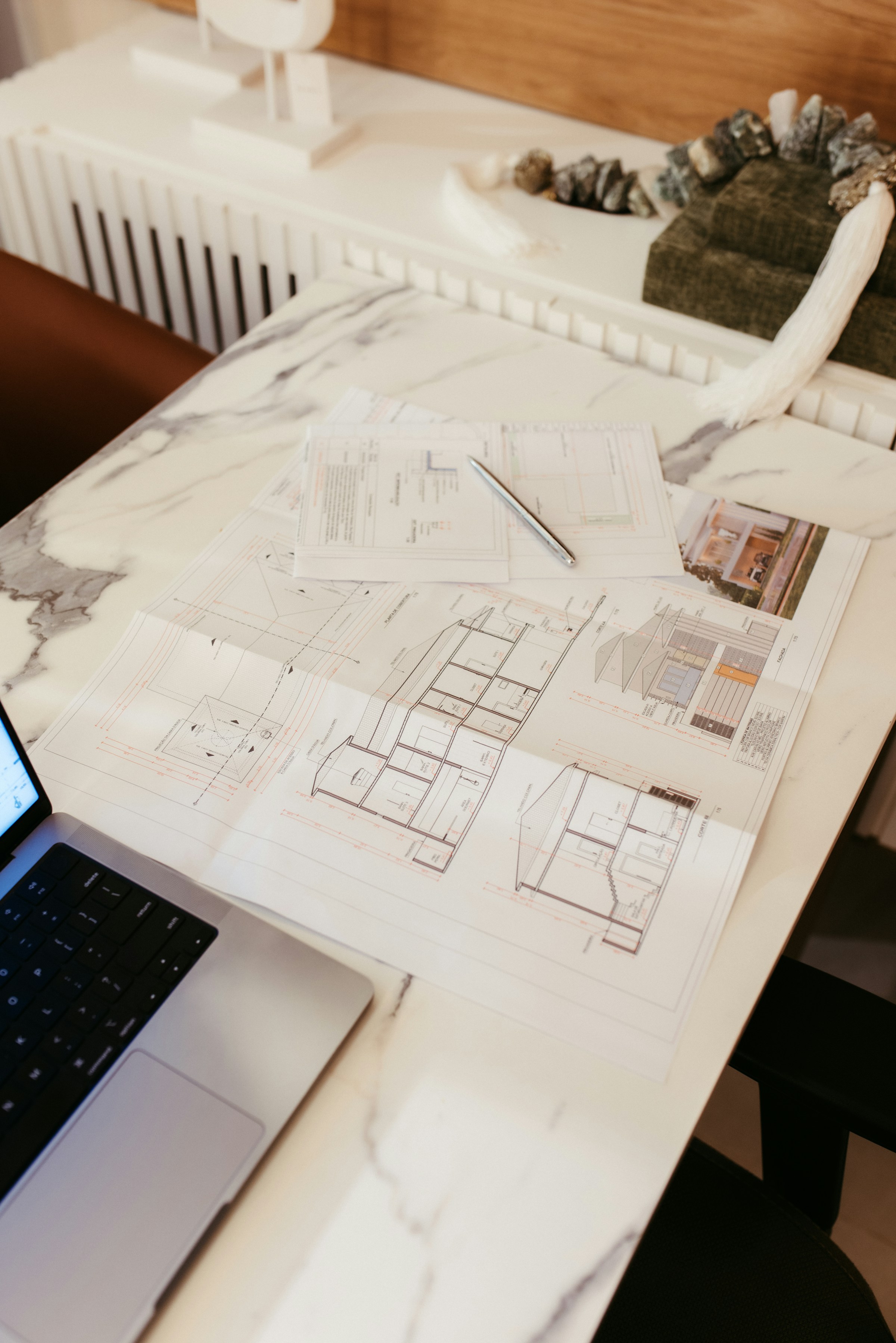 Architectural drawings and a laptop on a work surface