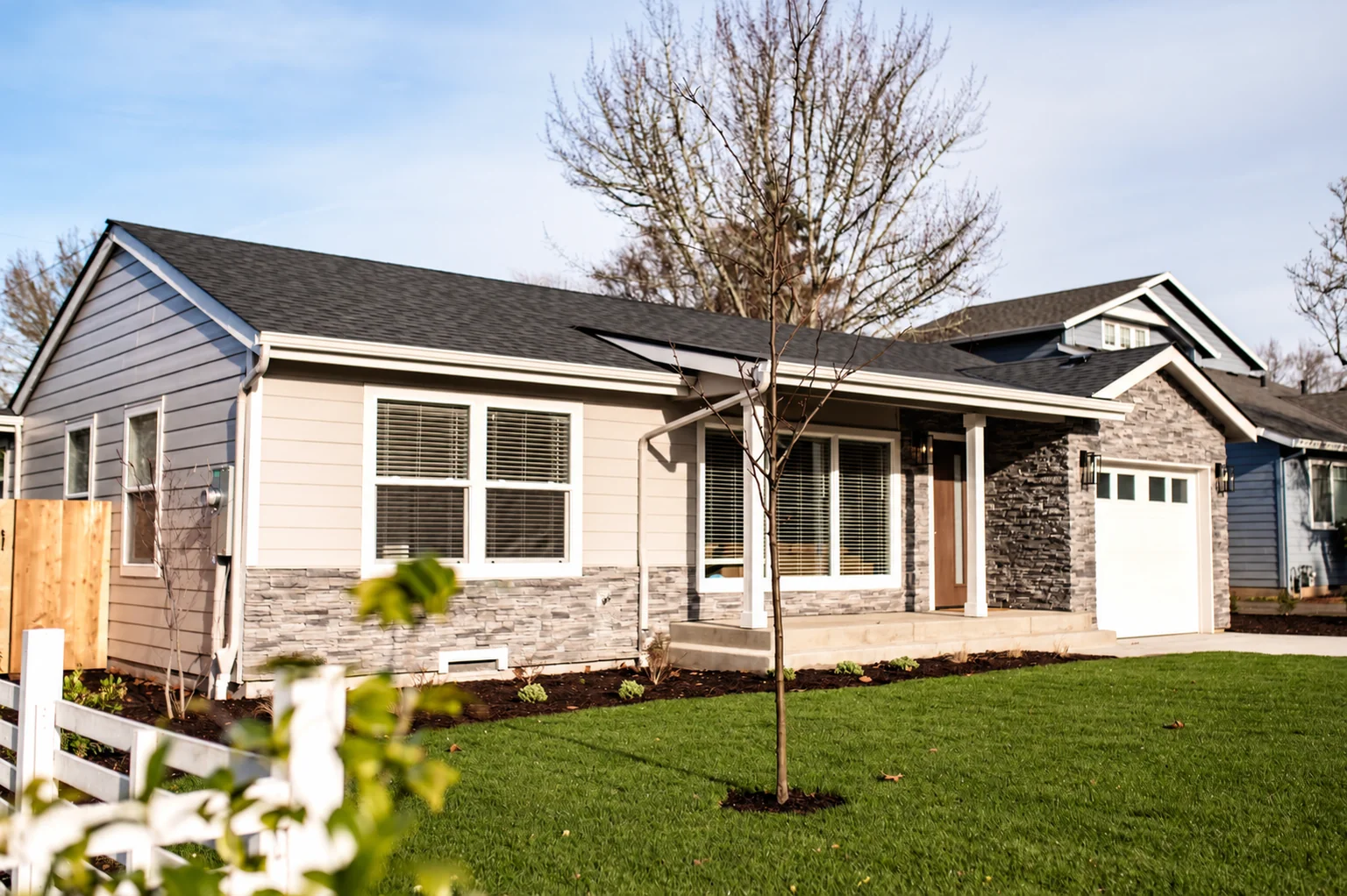 Resolution project home with horizontal siding, stone accents, a covered porch and landscaped lawn