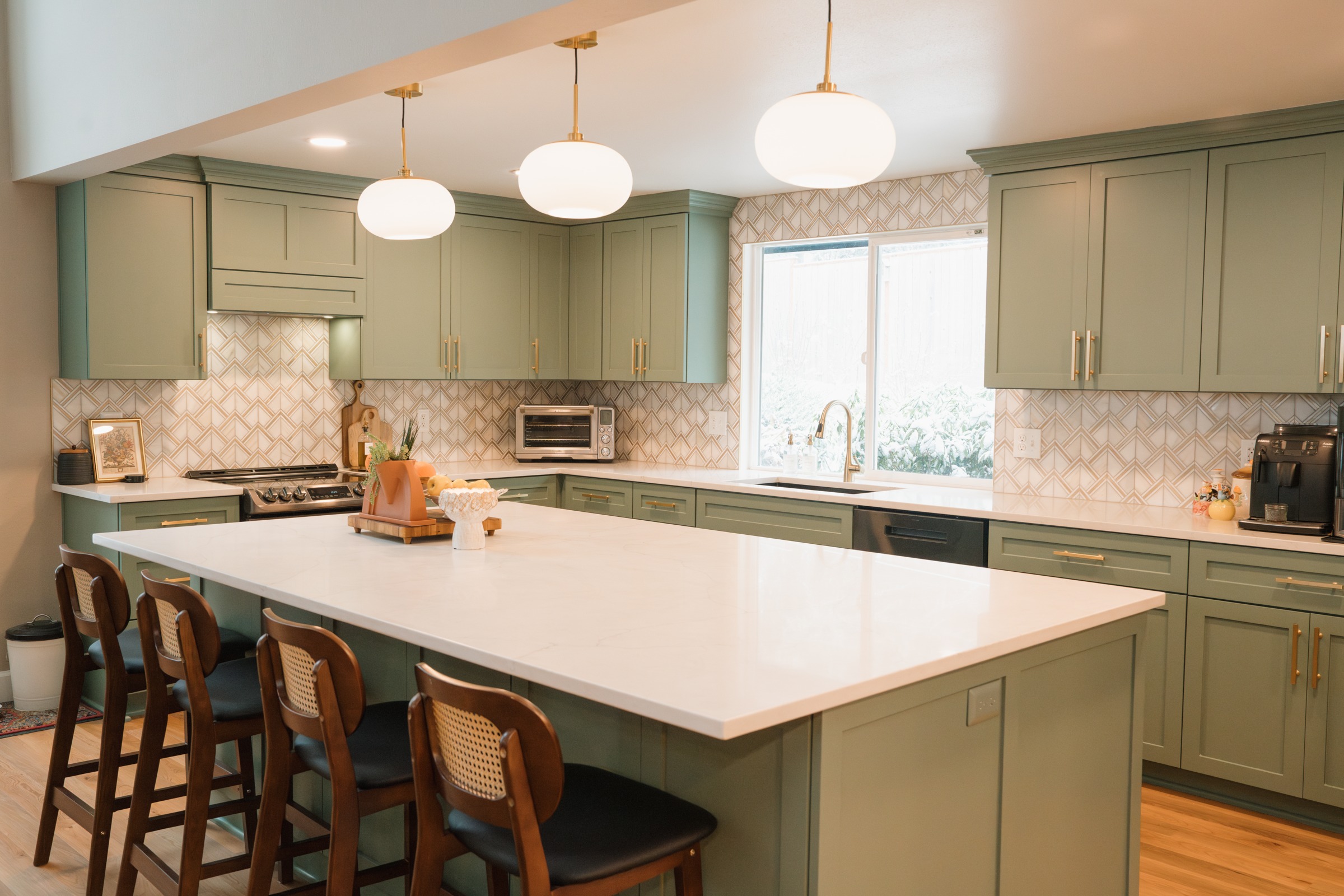 Resolution kitchen project with green cabinetry, a pale island, pendant lights and counter seating
