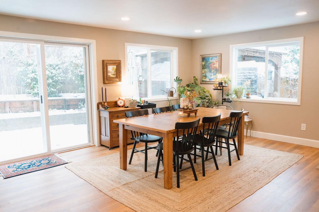 Dining area with wood flooring, white-trimmed windows on two sides and a sliding glass door toward the garden