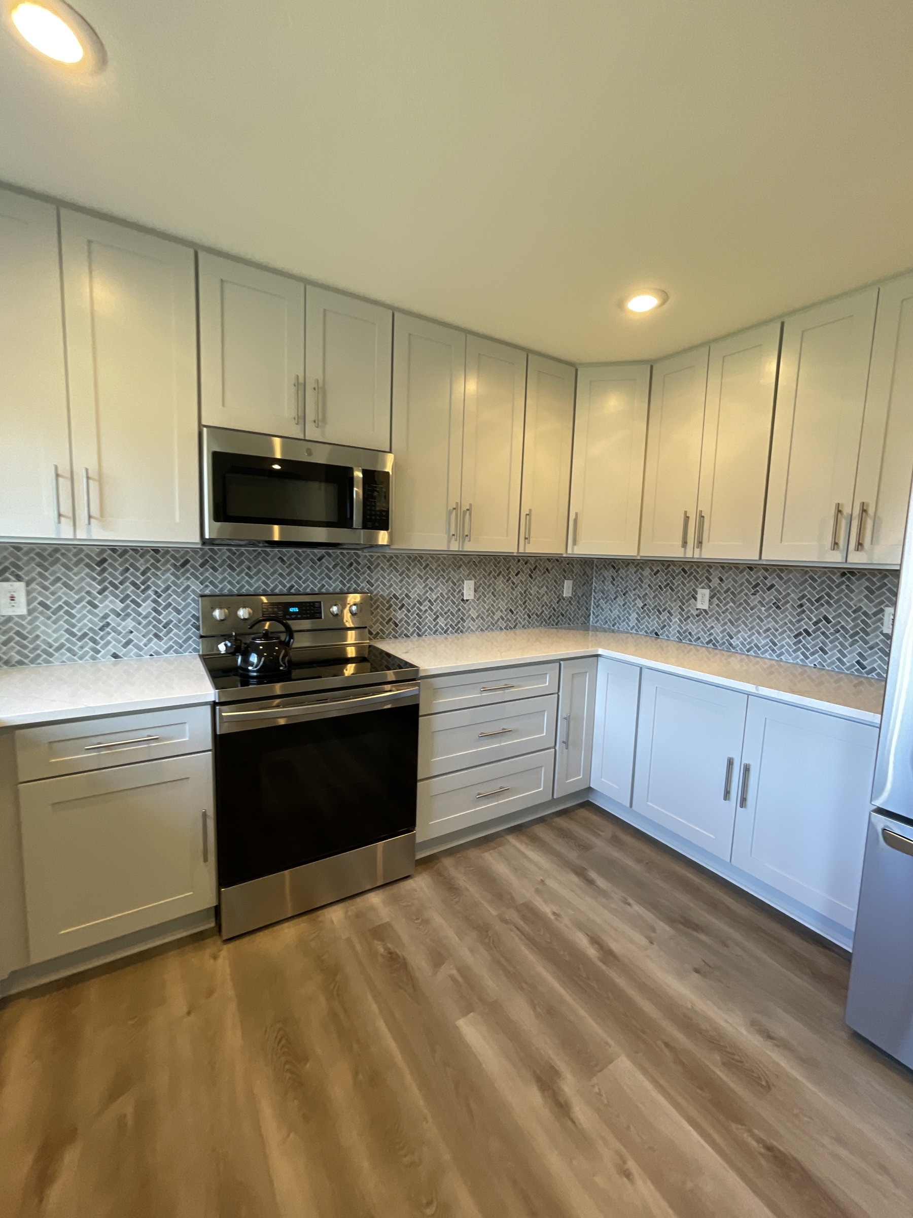 Light painted kitchen cabinetry, a range, and patterned backsplash