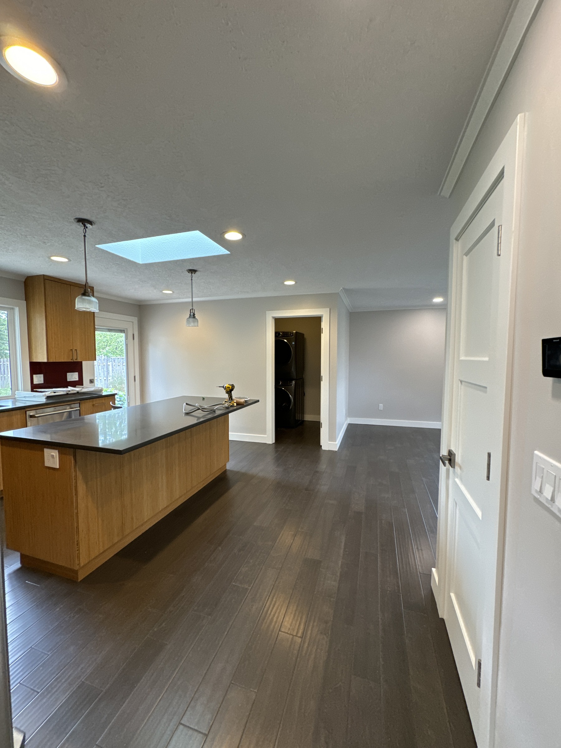 Interior remodel in progress with wood kitchen cabinetry, dark flooring, and tools on the island