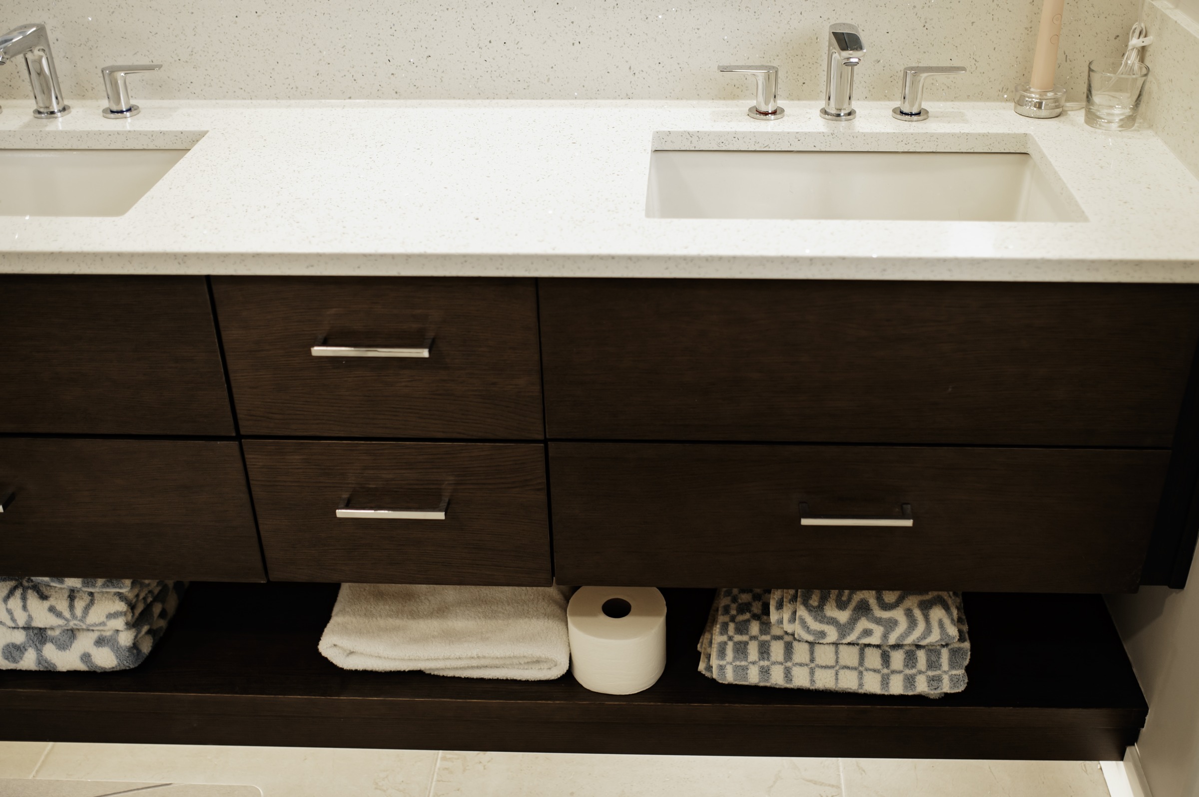 Dark bathroom vanity with drawers, open storage, and two sinks